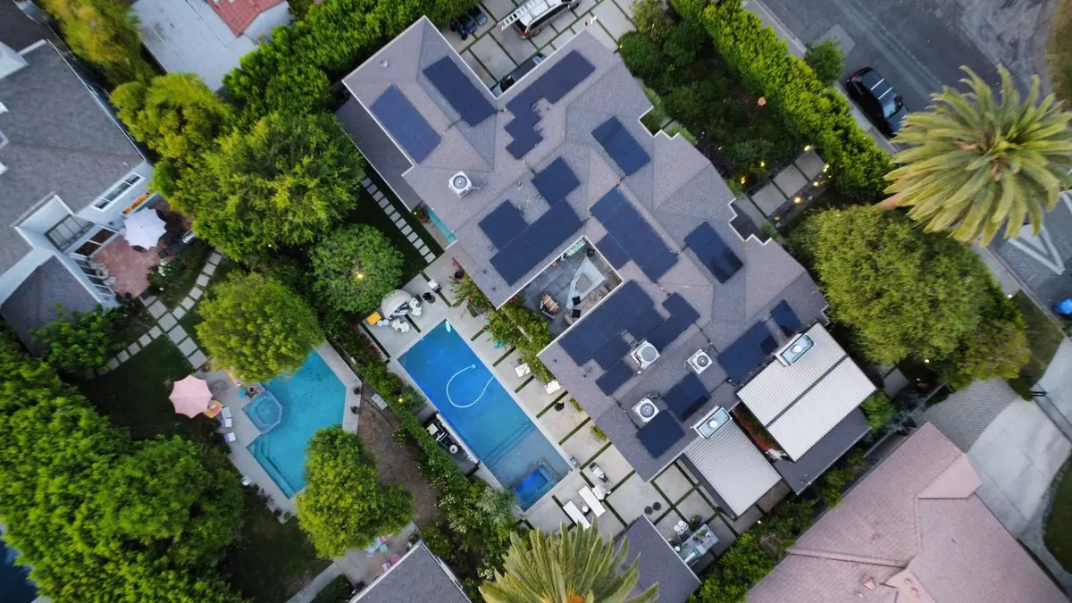 Aerial view of a large home with solar panels across a multi-level roof