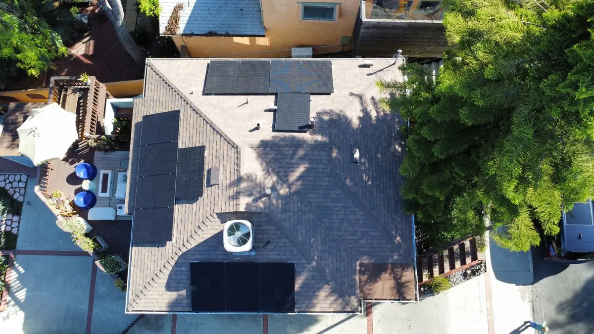 Aerial view of solar panels arranged around vents on a shingle roof