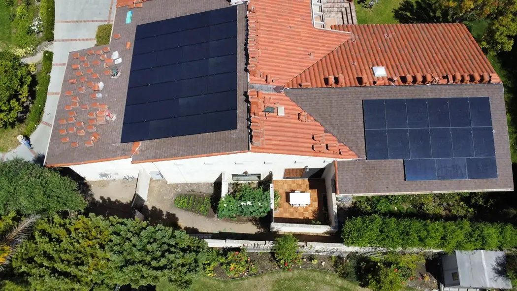Aerial view of solar panels on a roof with tile and shingle sections