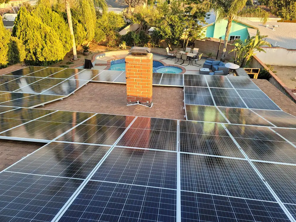 Rooftop solar array around a brick chimney, overlooking a backyard pool