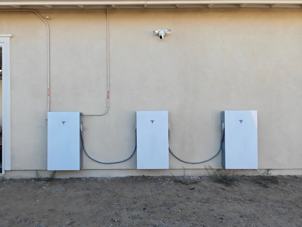 Three Tesla Powerwall batteries on an exterior wall